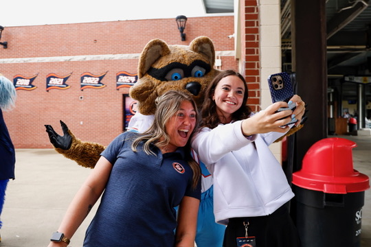 Evelyn taking a selfie with the Bowling Green Hot Rods mascot and a teammate